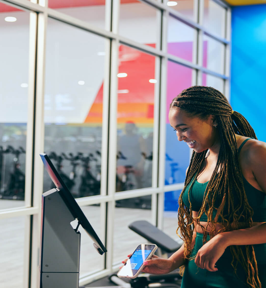 A woman scanning her phone to enter a premium amenity area at a fitness connection 